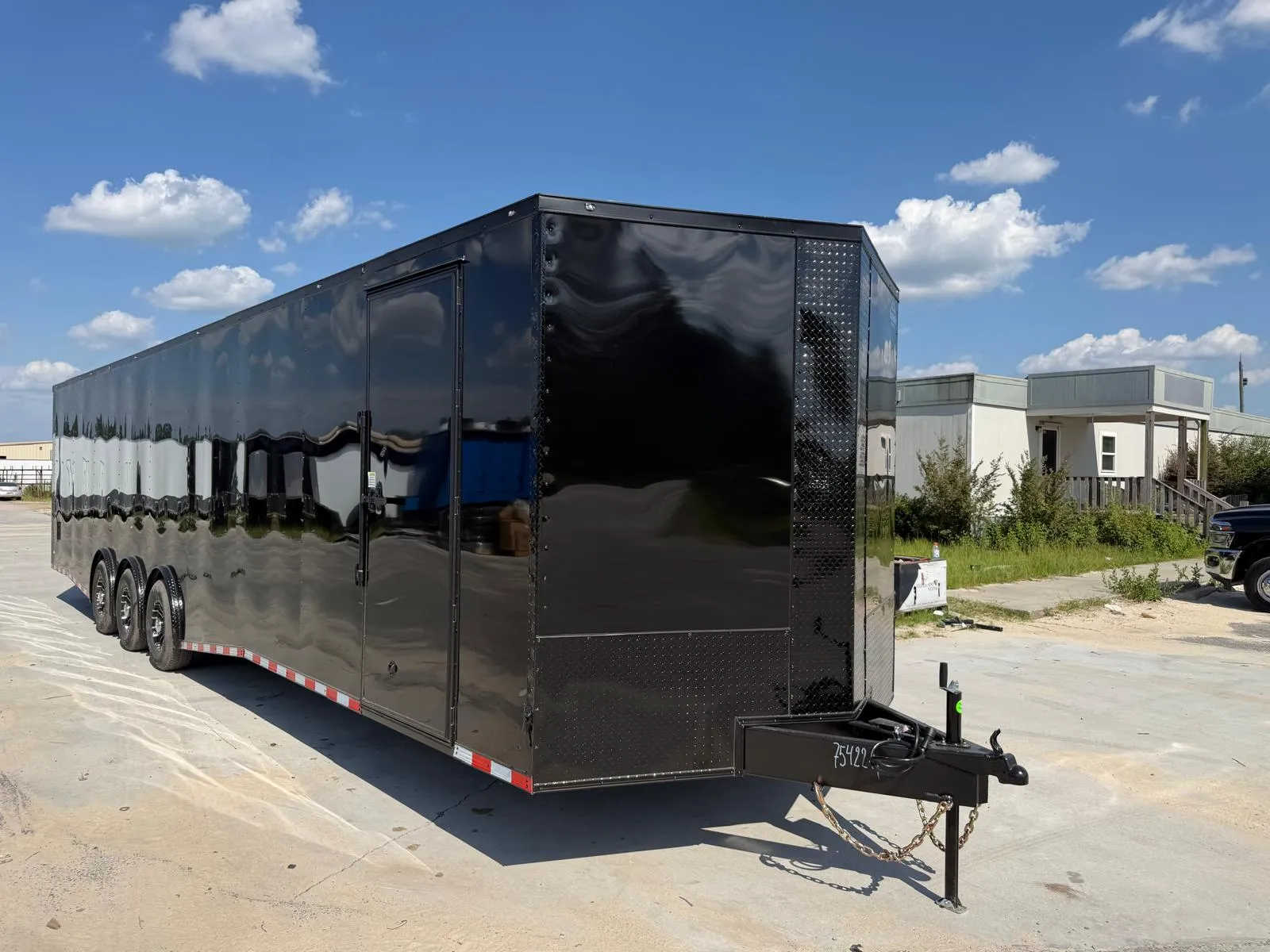 Black enclosed three-axle trailer, front three-quarter view