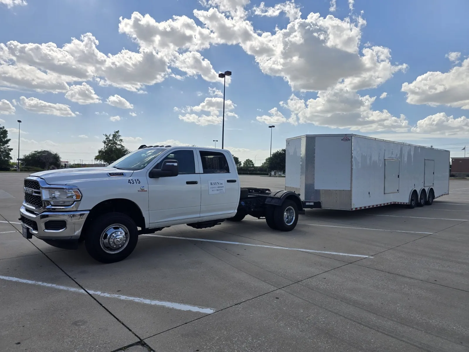 The Ram 3500 hitched to a white enclosed three-axle trailer under a wide Texas sky